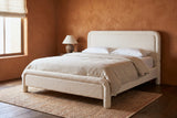 Casacalenda white boucle bed against a terracotta clay plaster wall in a Santa Fe bedroom with a dark pine floor and a woven rug
