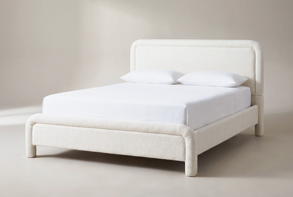 The Casacalenda bed in white boucle with a white mattress and pillows (not included), three-quarter view on a light studio backdrop