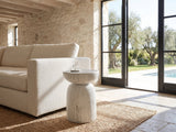 Casarano Fiber Concrete Hourglass Side Table beside a linen sofa in a poolside villa