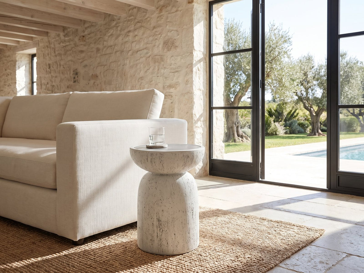 Casarano Fiber Concrete Hourglass Side Table beside a linen sofa in a poolside villa