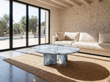 Cascia Compact Blue-Grey Marble Coffee Table on a jute rug in front of a linen sofa in a poolside villa