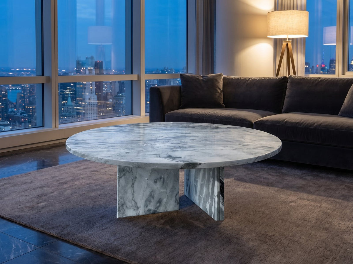 Cascia Compact Blue-Grey Marble Coffee Table on a wool rug in front of a velvet sofa in a city penthouse at blue hour