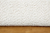 Close-up of the white boucle on the Casoli bed above the natural rubberwood plinth