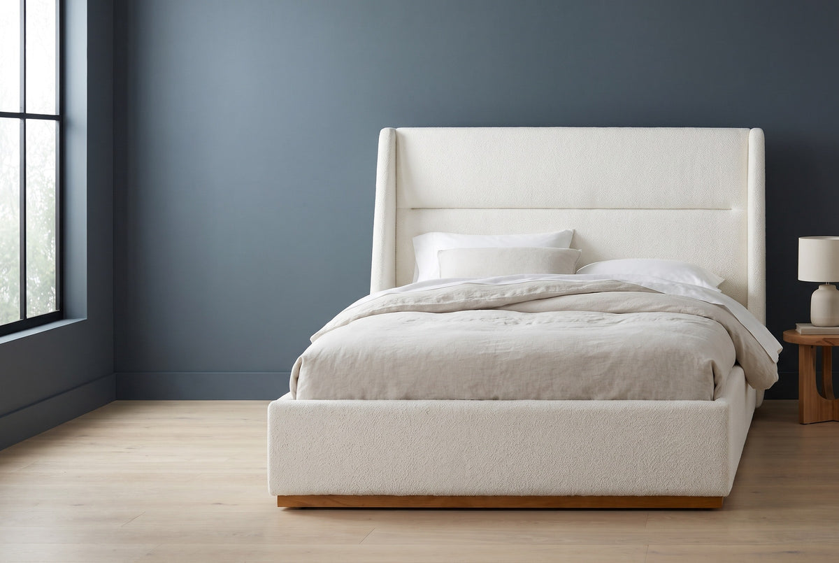 Casoli white boucle winged bed against a deep slate-blue wall in a Seattle bedroom, a tall black-framed window at the left