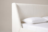 One wing and the plain headboard panel of the Casoli bed in white boucle, above a white pillow