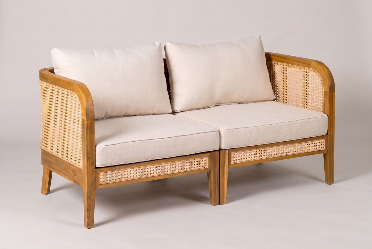 The Castelbuono left and right arm chairs joined as a loveseat, acacia frames with cane panels and beige cushions, three-quarter view on a light studio backdrop