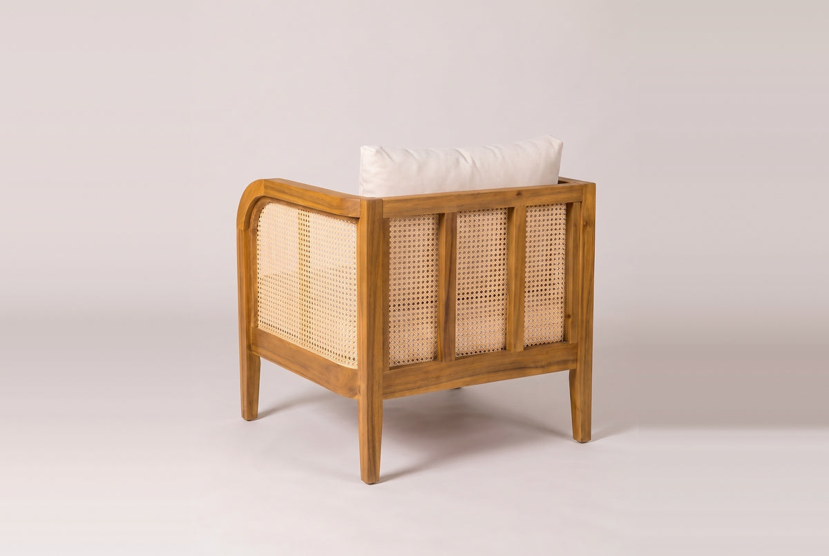 A Castelbuono arm chair from behind: three cane panels between acacia stiles, the rounded arm and the cane arm panel