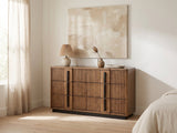 Castelfranco 65.5-Inch Ash Brown Reeded 6-Drawer Dresser against a plaster wall under an abstract canvas in a bright bedroom