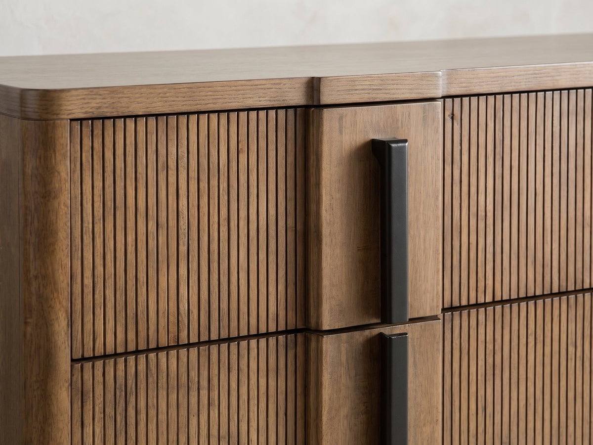 Close-up of the Castelfranco 65.5-Inch Ash Brown Reeded 6-Drawer Dresser: the reeded ash drawer fronts beside a flat strip with its black bar pull
