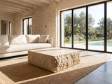 Castellina Faux Travertine Fiberglass Block Coffee Table on a jute rug in front of a linen sofa in a poolside villa