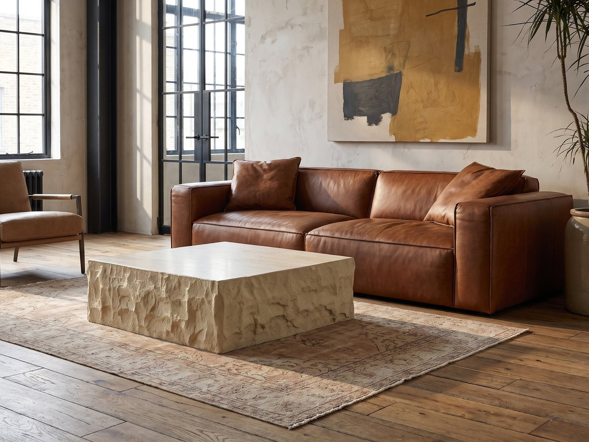 Castellina Faux Travertine Fiberglass Block Coffee Table on a vintage rug in front of a leather sofa in an industrial loft