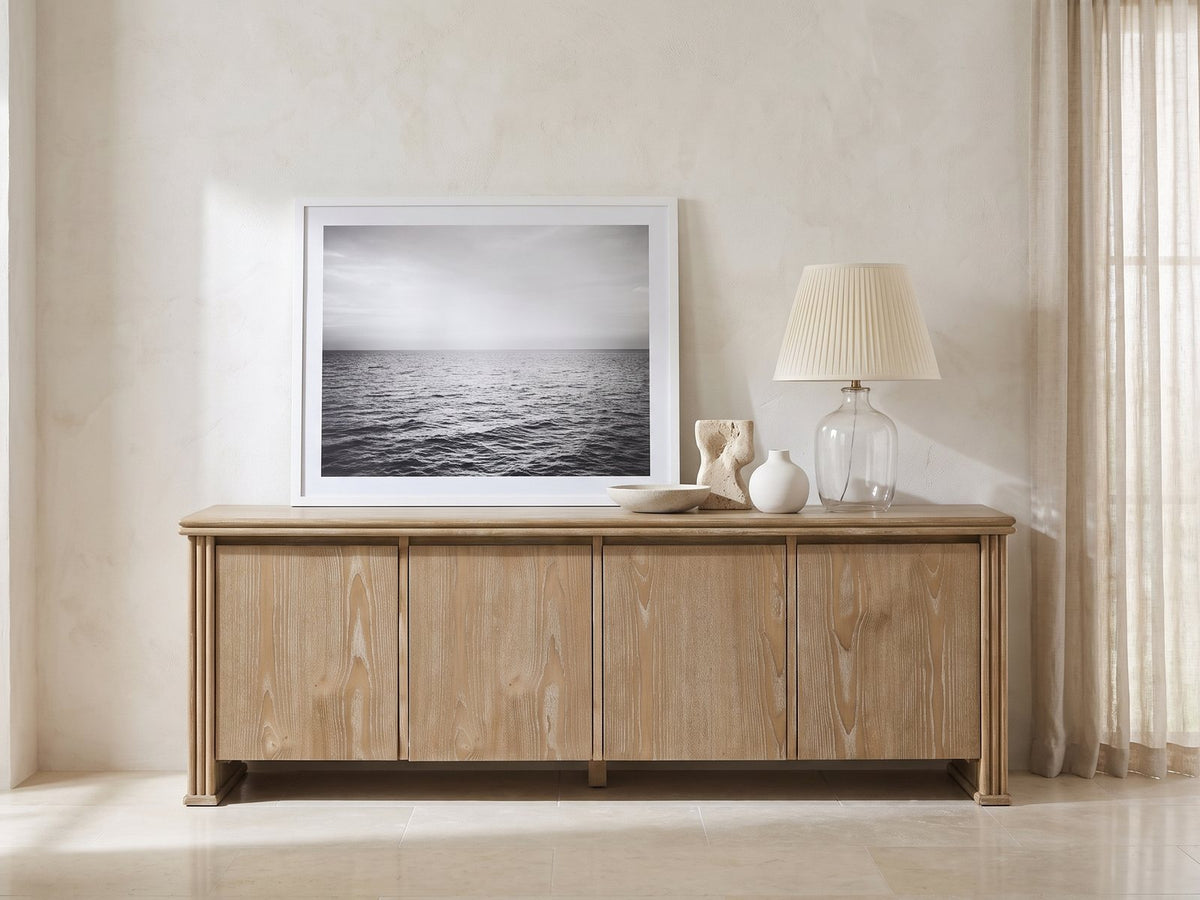 Cefalu Fluted Oak Media Console styled with a leaning print, a lamp and ceramics in a bright plaster room