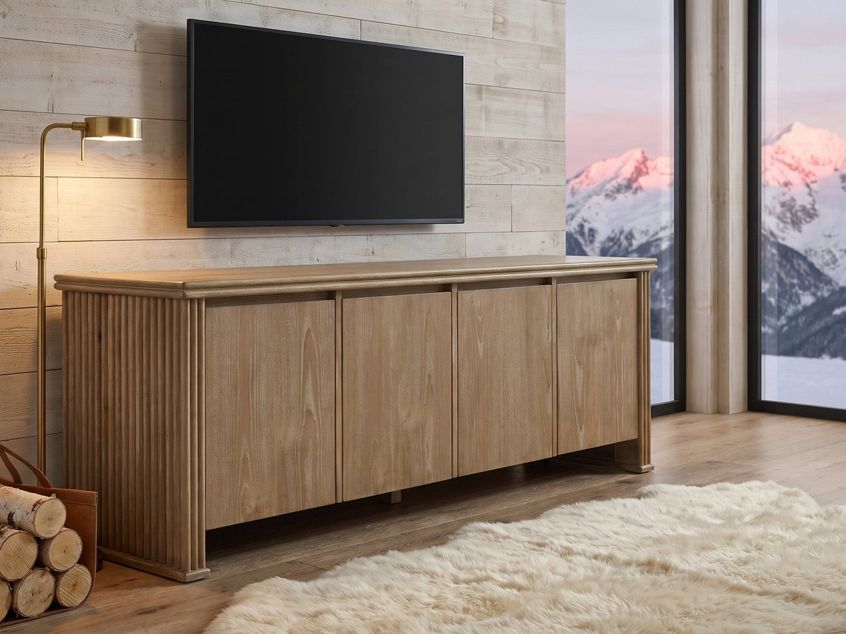 Cefalu Fluted Oak Media Console seen from the side, under a wall-mounted screen in an alpine chalet at dusk