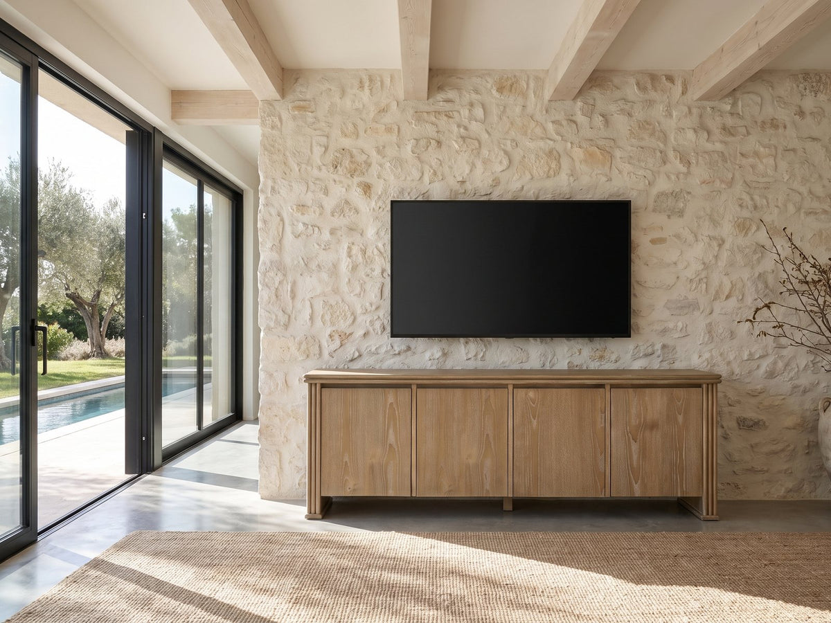 Cefalu Fluted Oak Media Console under a wall-mounted screen on a pale stone wall in a poolside villa