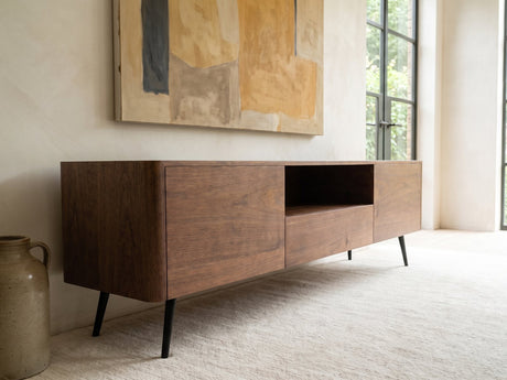 Cernobbio Curved Walnut Media Console seen from the side, under a large abstract painting in a bright living room