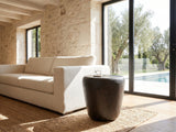 Cervara Rustic Bronze Metal Drum Side Table beside a linen sofa in a poolside villa