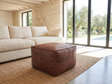 Cervo Distressed Brown Genuine Leather Square Pouf on a jute rug in front of a linen sofa in a poolside villa