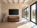 Cherasco Arch Mango Media Console under a wall-mounted screen on a pale stone wall in a poolside villa