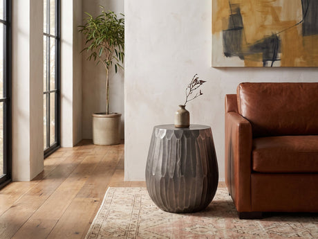 Chianciano Cast Aluminum Faceted Drum Side Table beside a leather sofa in an industrial loft