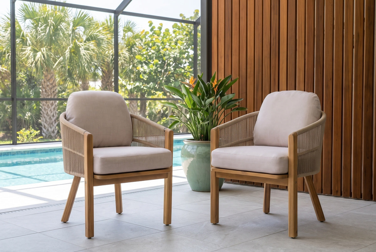 Two Chiaramonte dining armchairs in a screened pool lanai with a cedar slat wall, pale grey pavers and a celadon pot with a bird of paradise