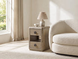 Chiaromonte Knotty Oak Veneer Two-Drawer Side Table with a lamp and a ceramic bowl beside a cream boucle armchair in a bright plaster room