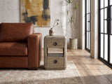 Chiaromonte Knotty Oak Veneer Two-Drawer Side Table beside a leather sofa in an industrial loft