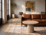 Chiavari Oak Veneer Round Pedestal Coffee Table on a vintage rug in front of a leather sofa in an industrial loft