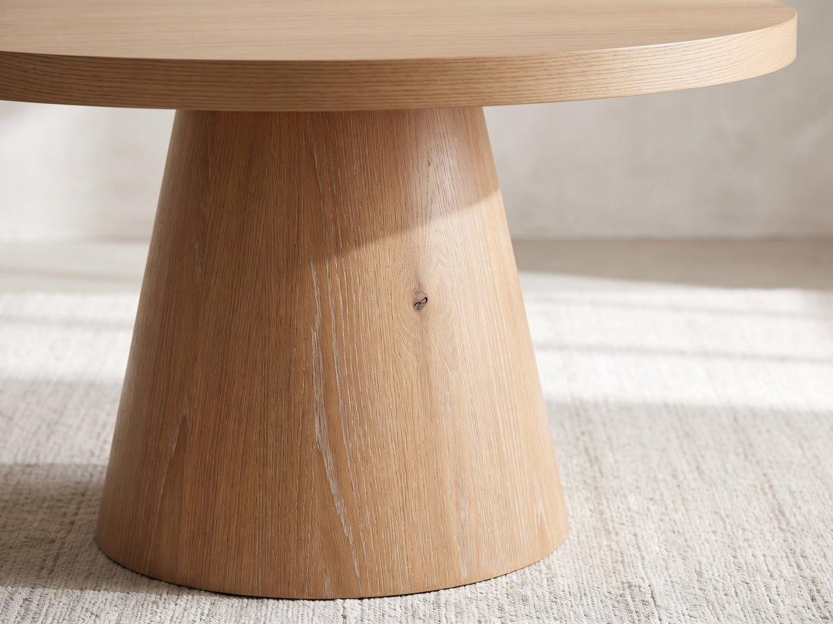 Close-up of the Chiavari Oak Veneer Round Pedestal Coffee Table: the cone pedestal widening to the floor under the round top