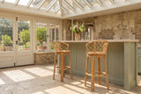 Cicala Natural Rattan Lattice-Back Bar Stool in an orangery