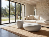 Cilento Grey Fiberglass Pebble Coffee Table and Side Table Set on a jute rug in front of a linen sofa in a poolside villa
