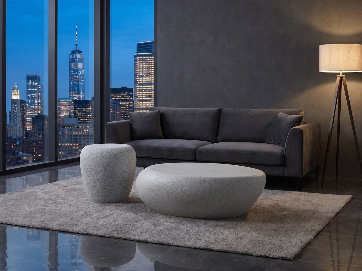 Cilento Grey Fiberglass Pebble Coffee Table and Side Table Set on a wool rug in front of a velvet sofa in a city penthouse at blue hour