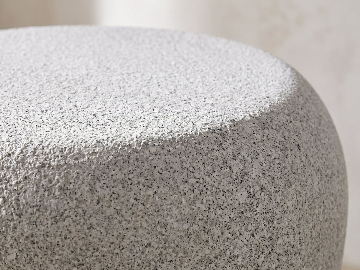 Close-up of the Cilento Speckled Grey Fiberglass Pebble Side Table: the rounded shoulder where the top rolls into the side