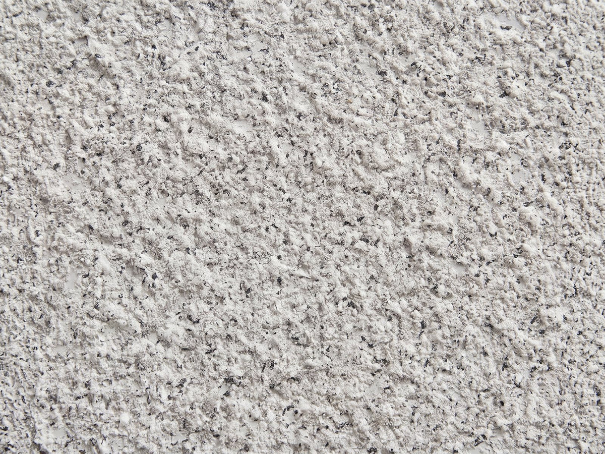 Close-up of the Cilento Speckled Grey Fiberglass Pebble Side Table: the speckled light grey stone-look finish of the fiberglass
