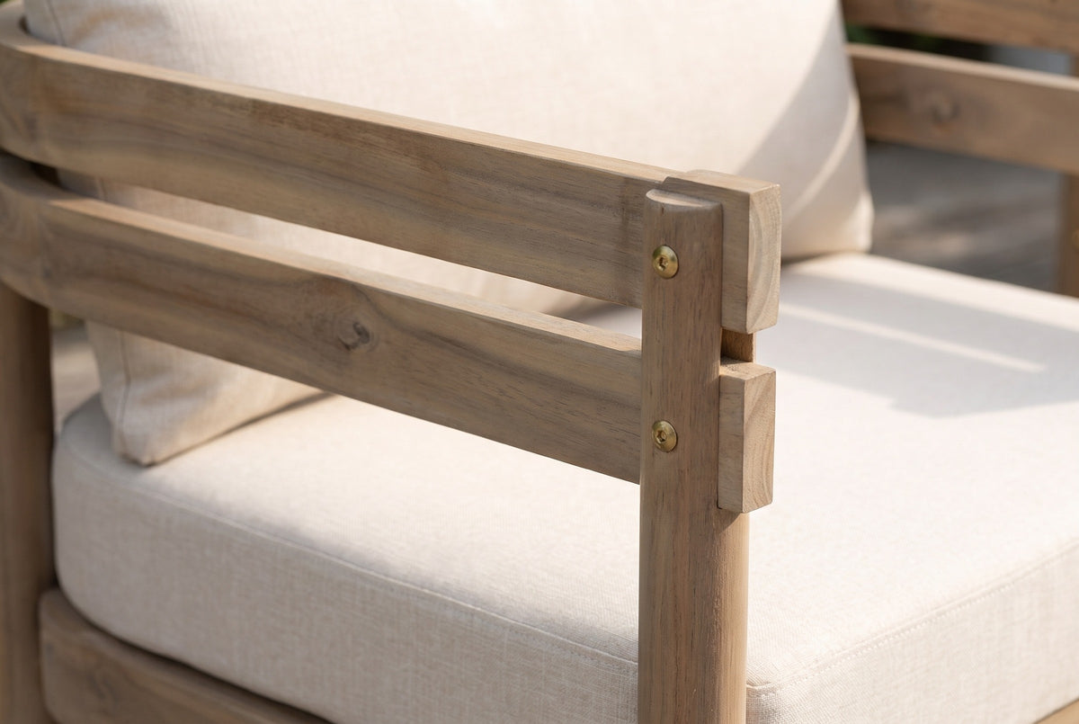 Close-up of a Cinisi arm: the two light brown acacia rails and the round front leg with brass-coloured screws, beside the beige cushions