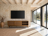 Cisternino 59-Inch Pecan Birch Veneer and Cane Media Console under a wall-mounted screen on a pale stone wall in a poolside villa
