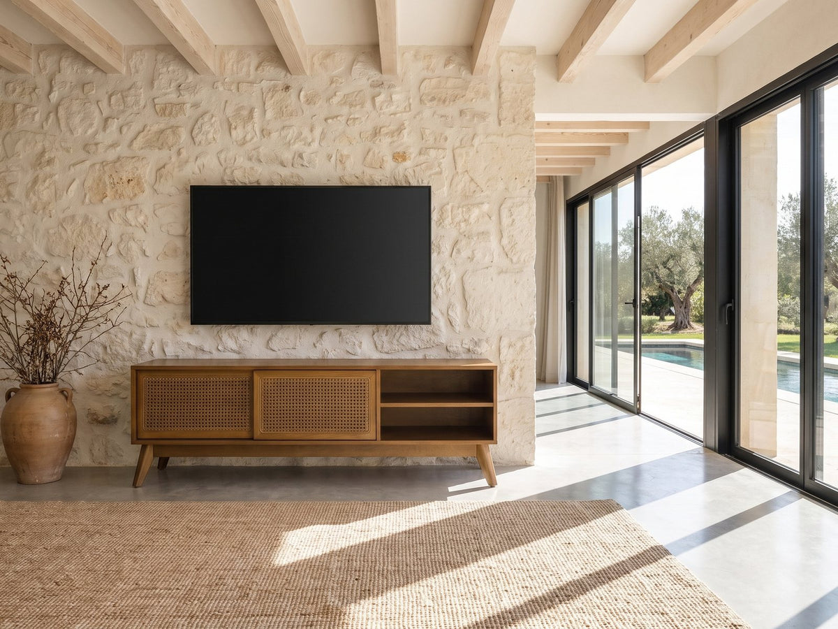 Cisternino 59-Inch Pecan Birch Veneer and Cane Media Console under a wall-mounted screen on a pale stone wall in a poolside villa