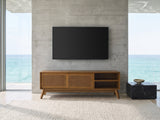 Cisternino 59-Inch Pecan Birch Veneer and Cane Media Console under a wall-mounted screen in an oceanfront glass house