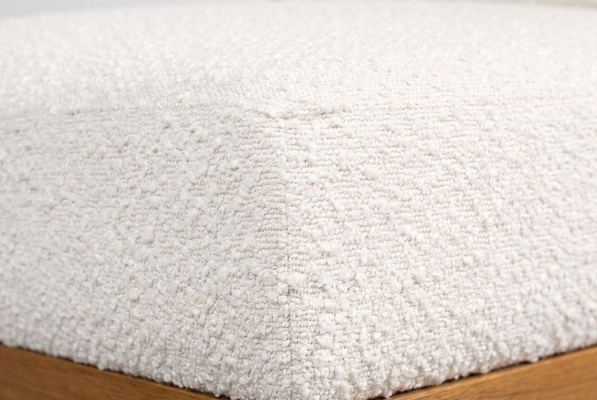 Close-up of the ivory boucle on the Citerna cushion: a dense, nubby weave of tiny loops, with the honey-brown frame below