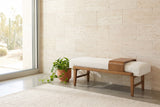 Citerna ivory boucle bench against a pale travertine stone wall in a Palm Springs living room, with a potted pothos beside it, a cream wool rug and a sliding glass door looking onto the desert (plant and rug not included)