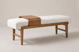 The Citerna bench with its ivory boucle cushion, honey-brown frame and wood tray, three-quarter view on a light studio backdrop