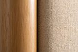 Close-up of the Civitella bed where a light walnut rubberwood post meets the beige woven headboard fabric