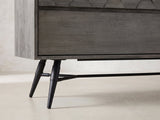Close-up of the Codroipo 61-Inch Gray Acacia Honeycomb Dresser: the splayed black metal leg and stretcher rod