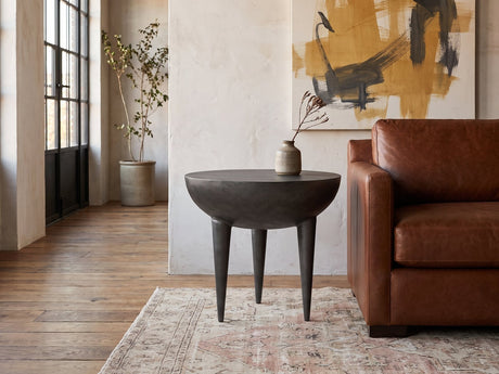 Colledara Cast Aluminum Bowl Side Table beside a leather sofa in an industrial loft