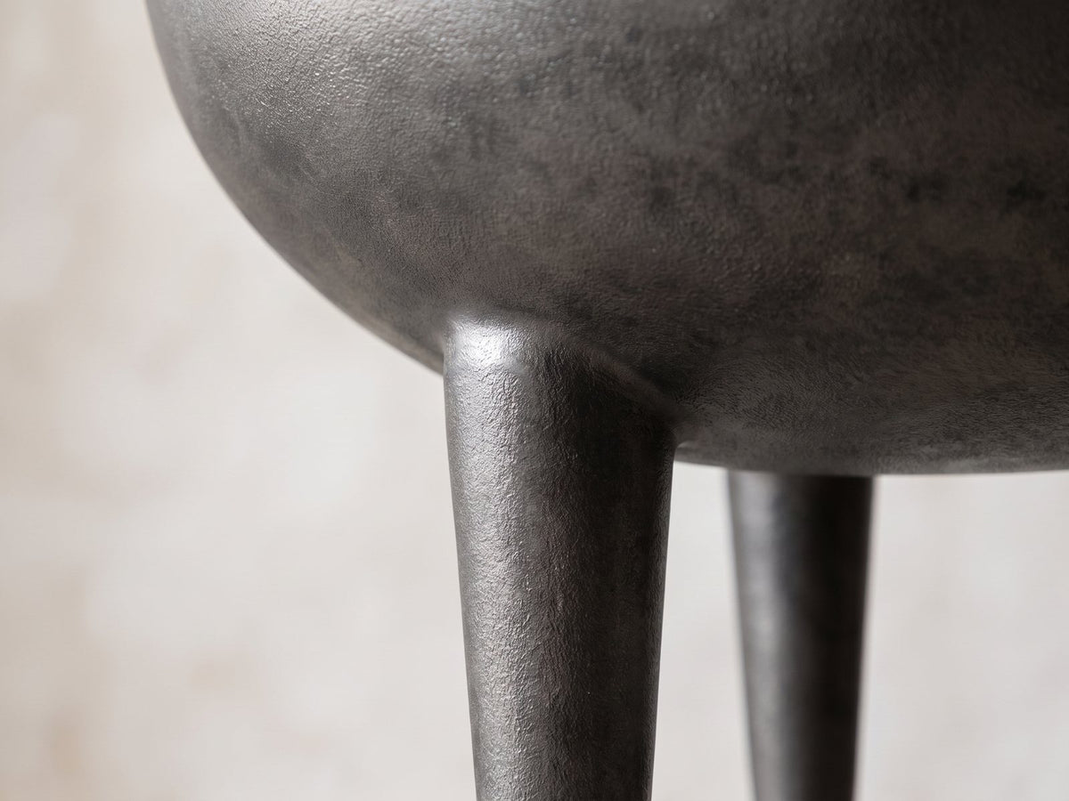 Close-up of the Colledara Cast Aluminum Bowl Side Table: a tapered cast leg growing out of the curve of the bowl