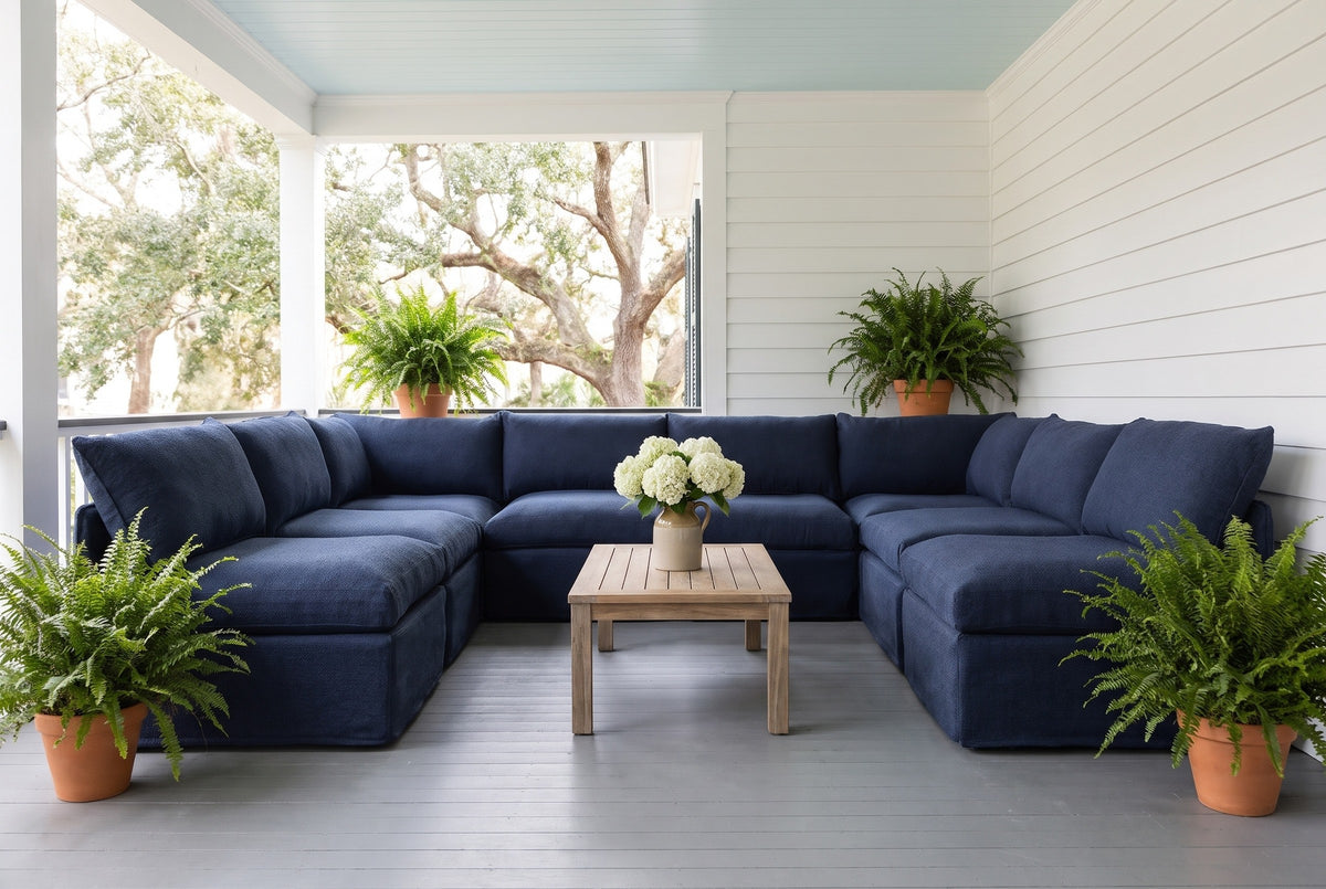 Comiso navy U-shaped sectional on a covered porch in Beaufort, South Carolina, with white board walls, a pale blue ceiling and ferns (coffee table not included)