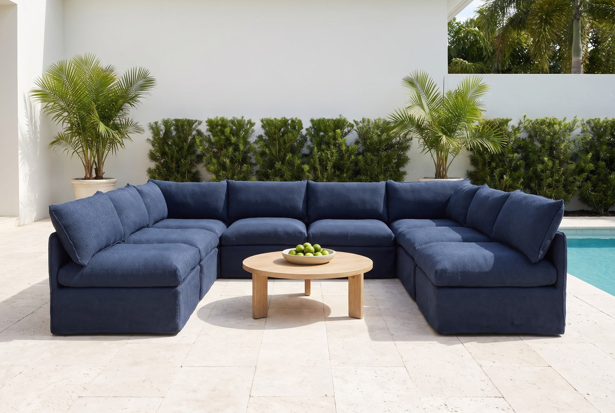 Comiso navy U-shaped sectional on an ivory travertine pool terrace at a Naples, Florida house, with palms and a clipped hedge (coffee table not included)