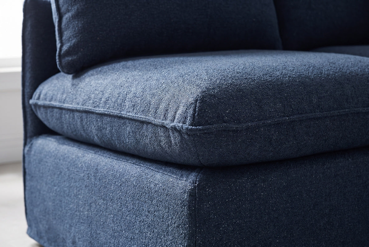 Close-up of the textured navy fabric on a Comiso seat: the piped cushion edge over the slipcovered base