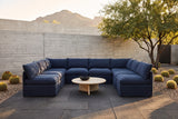 Comiso navy U-shaped outdoor sectional in a Paradise Valley, Arizona courtyard at golden hour, a board-formed concrete wall, basalt pavers and golden barrel cacti (coffee table not included)