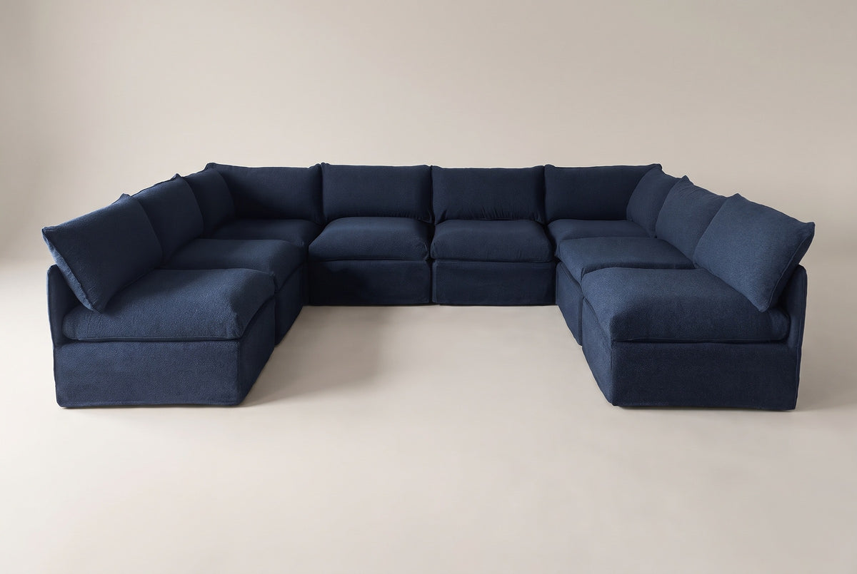 The Comiso eight-seat U-shaped sectional in navy slipcovers, seen from the open front of the U on a light studio backdrop