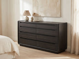 Conegliano 66-Inch Burnished Black 8-Drawer Dresser against a plaster wall under an abstract canvas in a bright bedroom